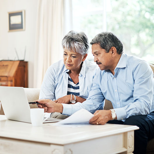 older couple doing paperwork and looking at a laptop