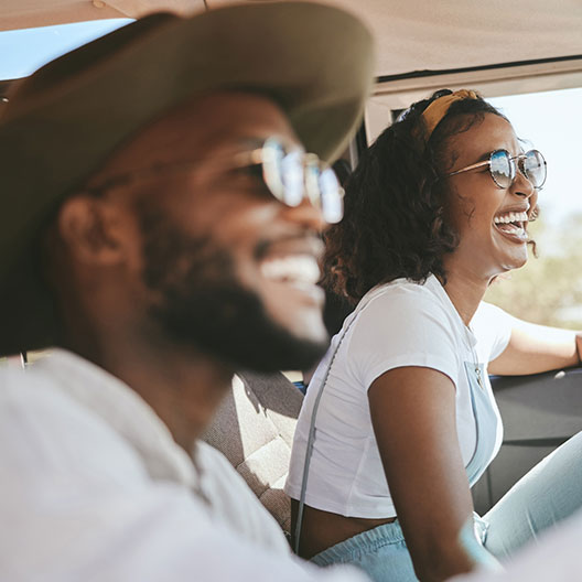 man and woman wearing sunglasses and smiling while driving car