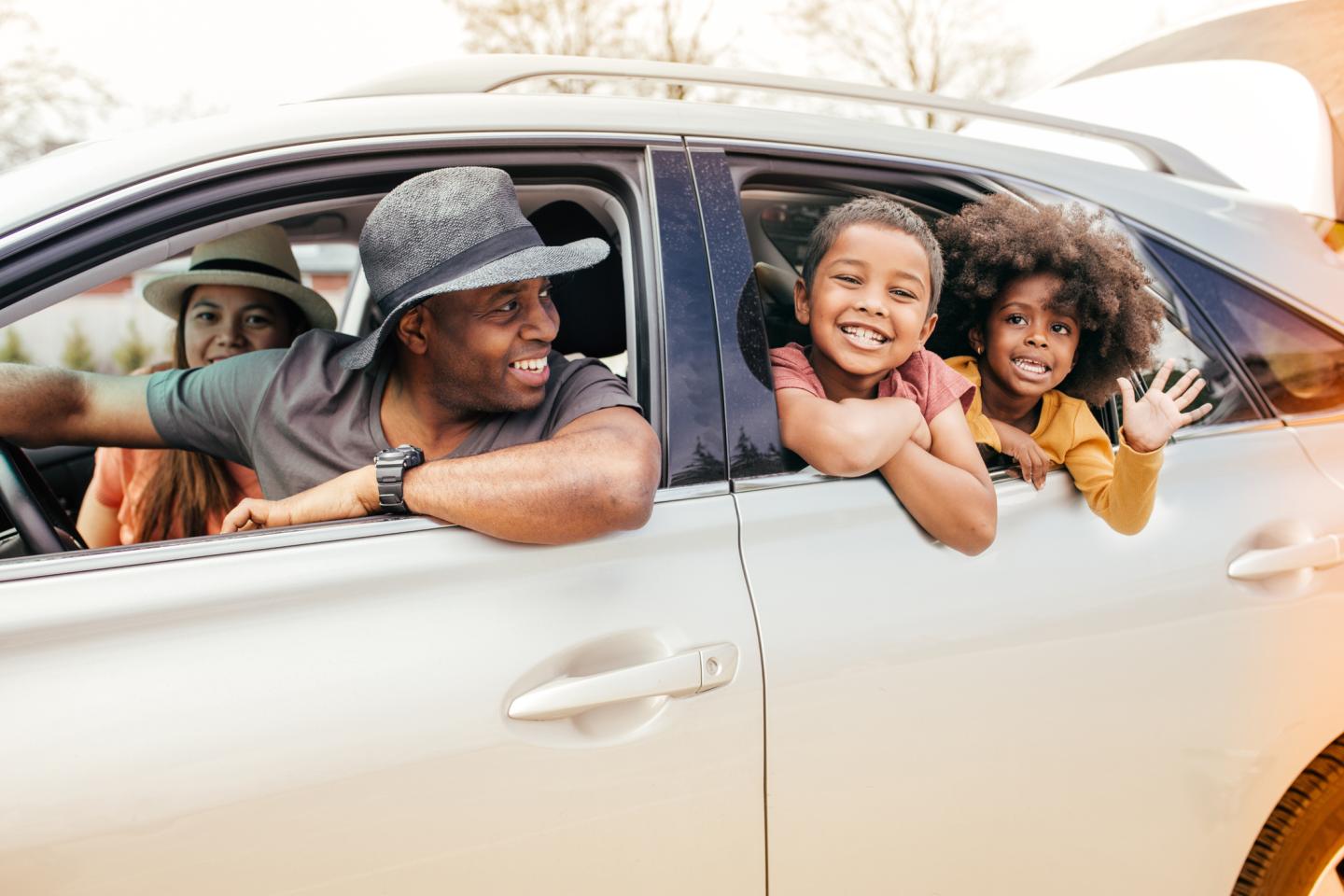 family in a car smiling and hanging out of the window