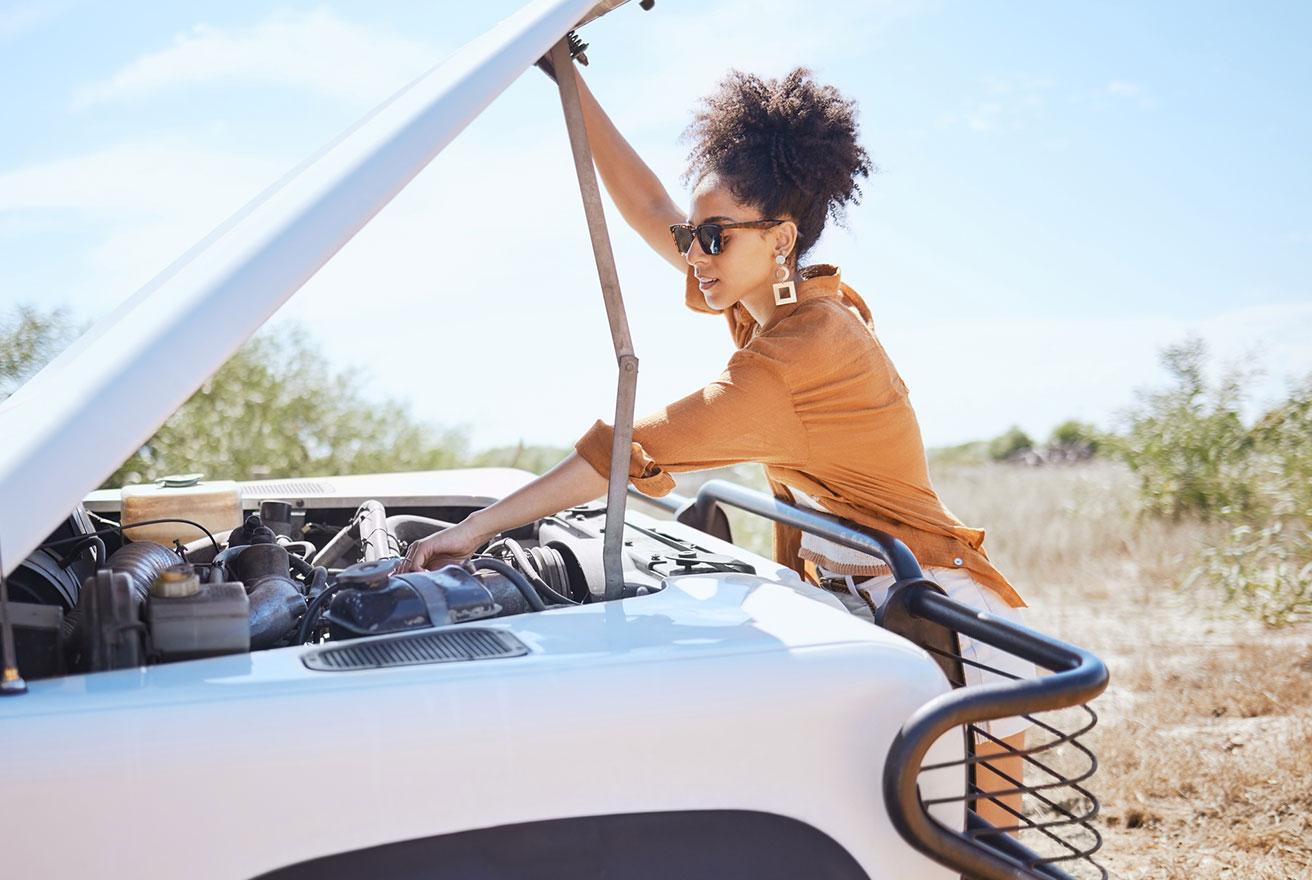 woman looking under the trunk of her car